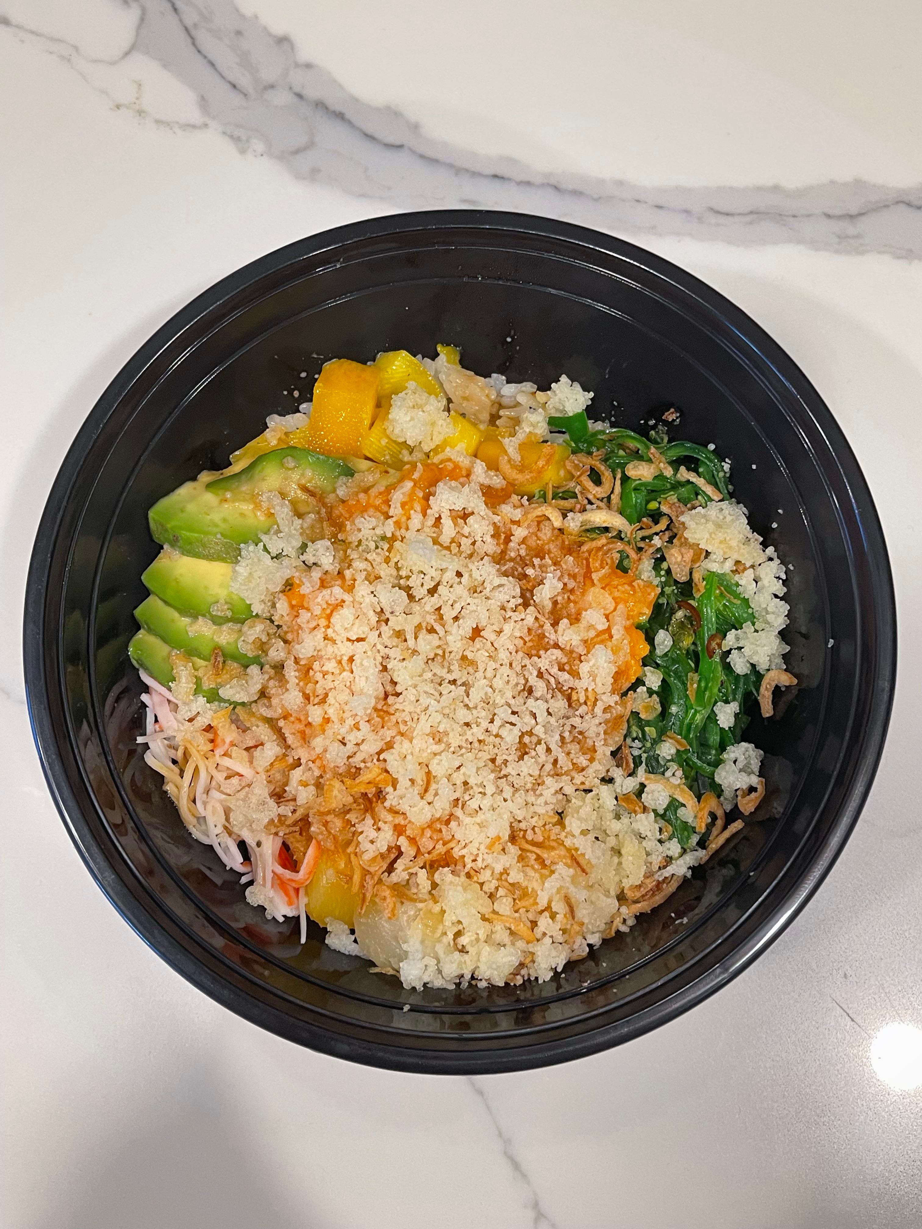 Yummy spicy salmon poke bowl with Kani, mango, avocado, seaweed salad