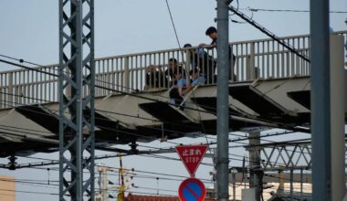 A young woman sits on the railway premises, causing one and a half hour delay on Tobu Tojo Line trains during rush hour
